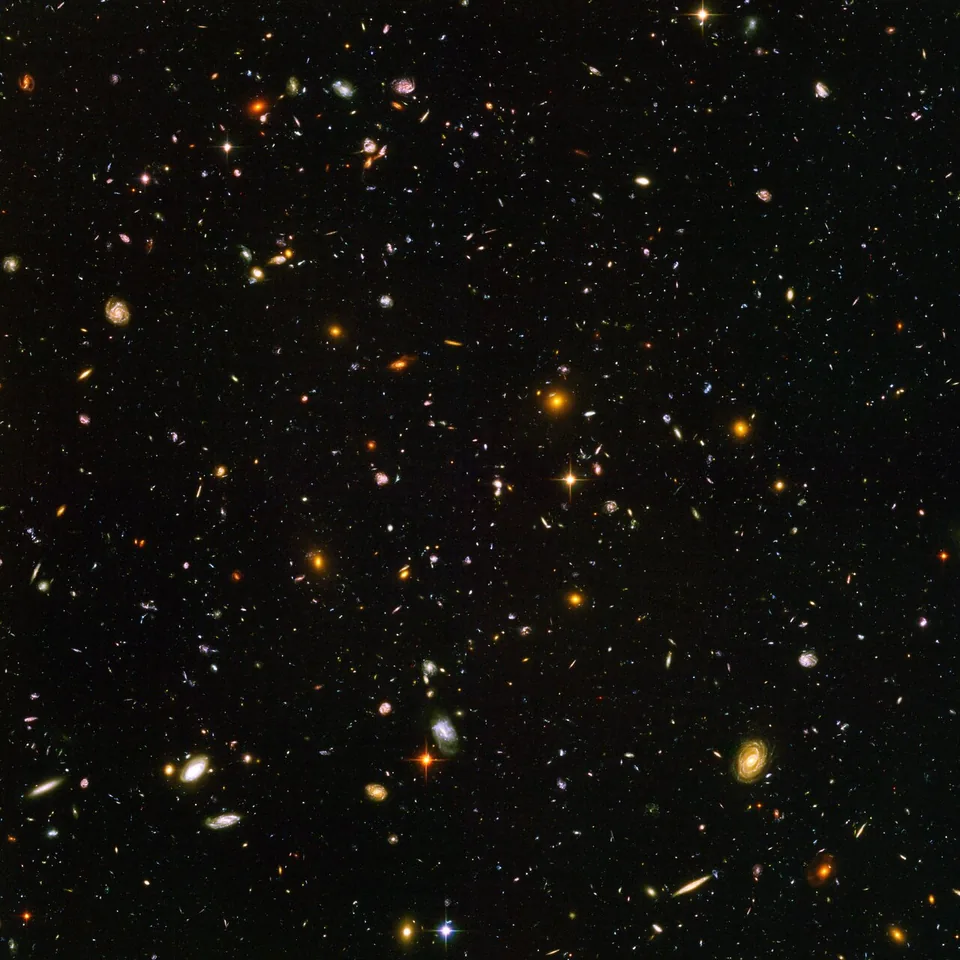 A small dark patch of sky contains many galaxies with different shapes, apparent sizes and colours.