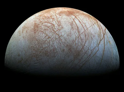 Dark branching fractures cross Europa's pale icy surface, interrupted by disrupted patches.