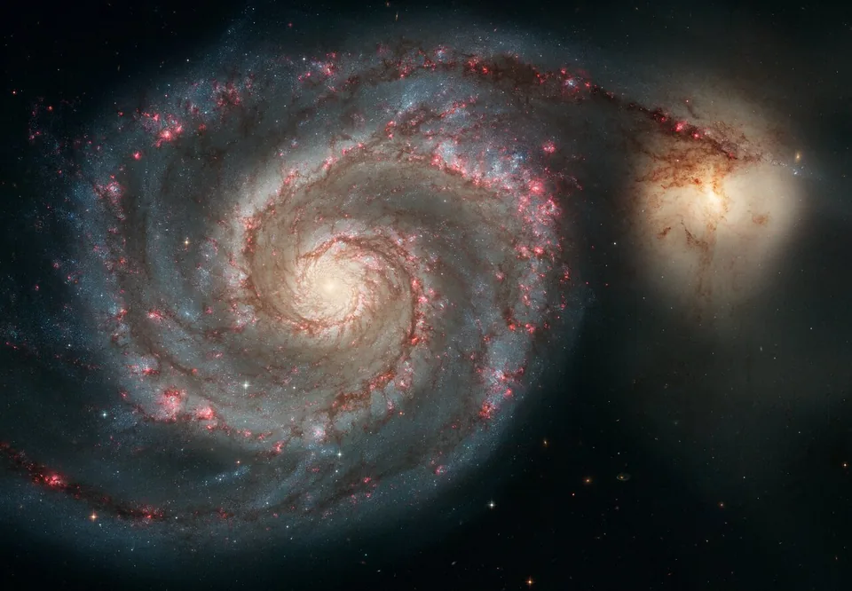 Two prominent spiral arms curve around M51's bright centre, while a smaller companion lies beside the outer disk.