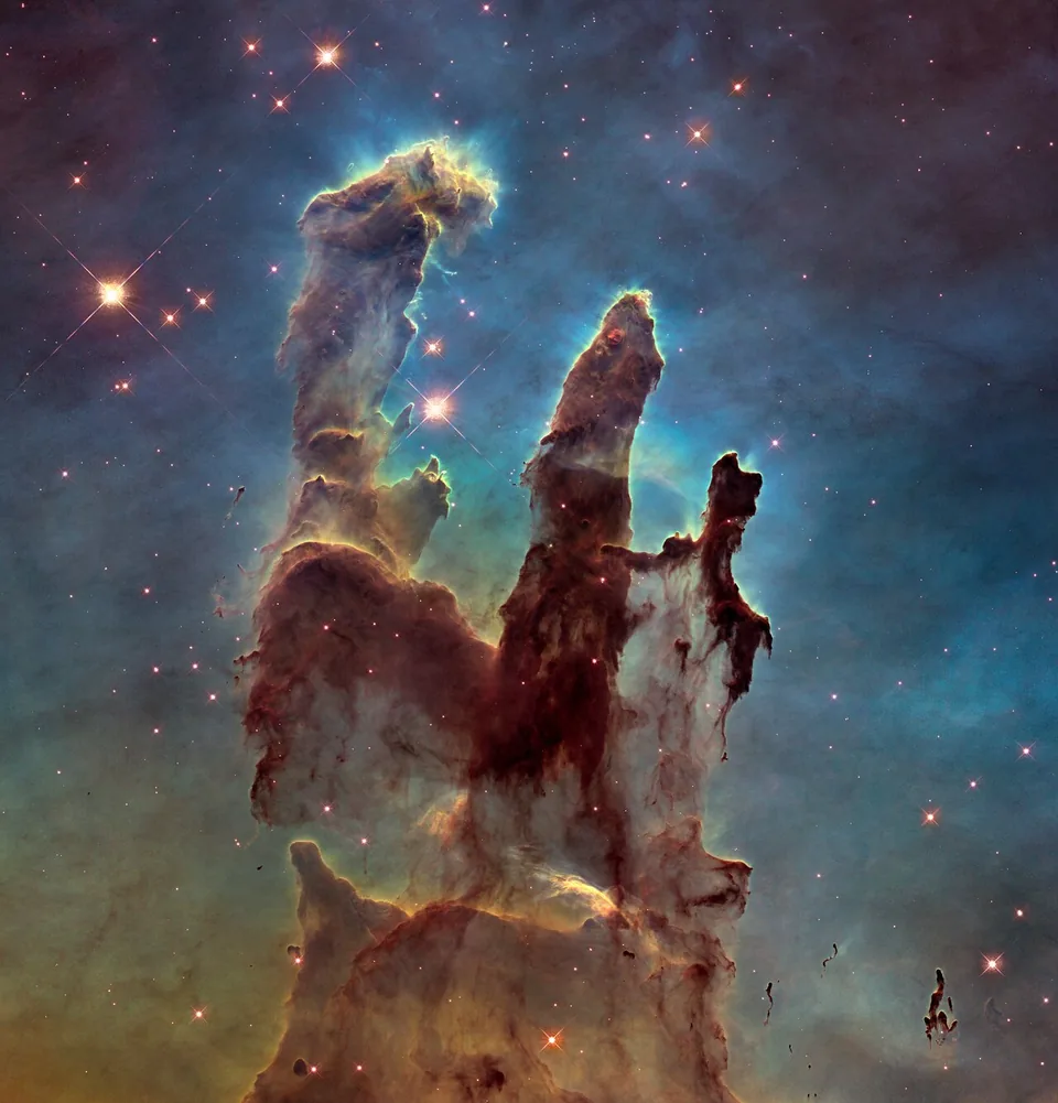 Dense dark pillars stand against glowing gas, with many stars obscured in this visible-light view.